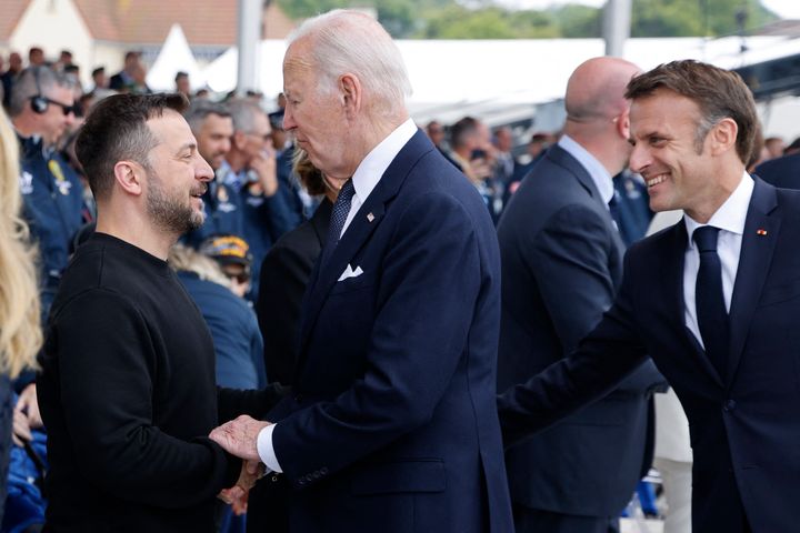 TOPSHOT - US President Joe Biden (C) shakes hands with Ukraine's President Volodymyr Zelensky (L) as France's President Emmanuel Macron (R) looks on during the International commemorative ceremony at Omaha Beach marking the 80th anniversary of the World War II "D-Day" Allied landings in Normandy, in Saint-Laurent-sur-Mer, in northwestern France, on June 6, 2024. The D-Day ceremonies on June 6 this year mark the 80th anniversary since the launch of 'Operation Overlord', a vast military operation by Allied forces in Normandy, which turned the tide of World War II, eventually leading to the liberation of occupied France and the end of the war against Nazi Germany. (Photo by Ludovic MARIN / AFP) (Photo by LUDOVIC MARIN/AFP via Getty Images)