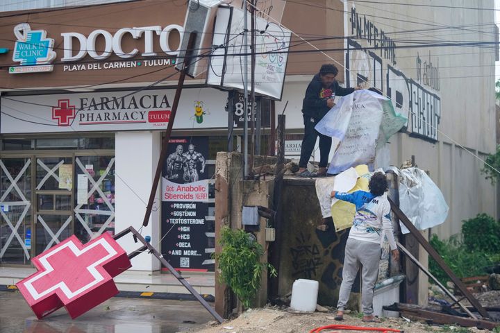 Residents clean up the entrance of a drugstore damaged by Hurricane Beryl in Tulum, Mexico, Friday, July 5, 2024. (AP Photo/Fernando Llano)