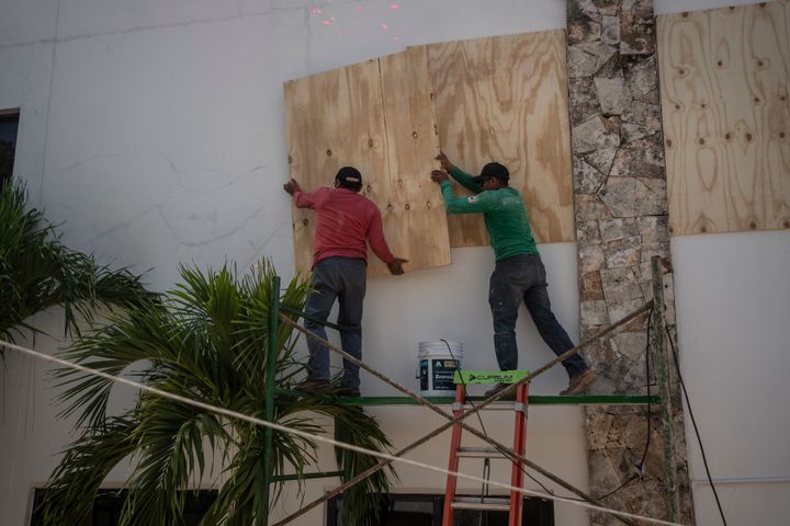 Workers protect a government building from the effects of Hurricane Beryl with wooden planks in Tulum, Mexico. (Photo by Felix Marquez/picture alliance via Getty Images)