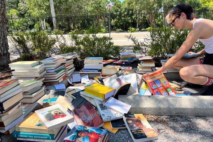 FILE - A student goes through books before they are sent to the landfill on the New College of Florida campus in Sarasota, Fla., Thursday, Aug. 15, 2024. (Steven Walker/Sarasota Herald-Tribune via AP)