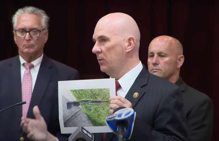 Nassau County officials hold up a photo of the shotgun they say was used in the killings at a Long Island, New York, home.