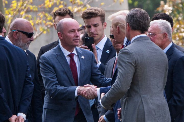 Utah Gov. Spencer Cox, left, shakes hands with former President Donald Trump at Virginia's Arlington National Cemetery on Monday.