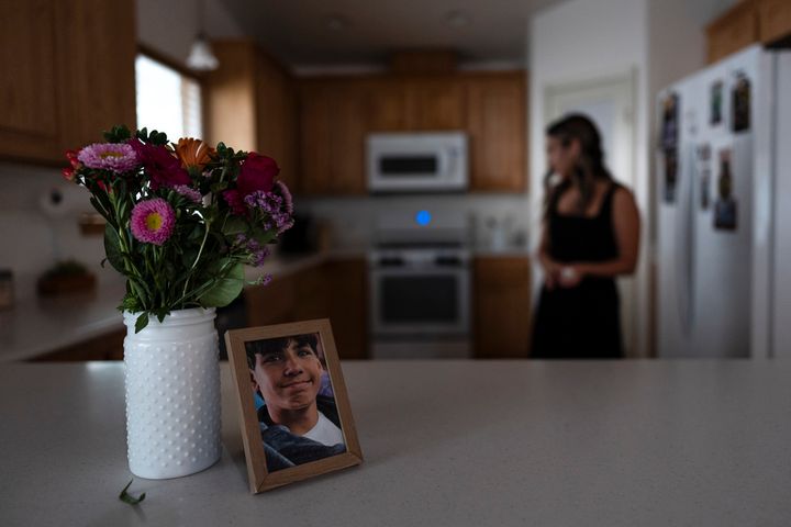 A framed photo of Elijah Ott, who died of a fentanyl overdose at 15, stands next to a vase of flowers as his mother, Mikayla Brown, works in the kitchen in Atascadero, California, Friday, Aug. 2, 2024.