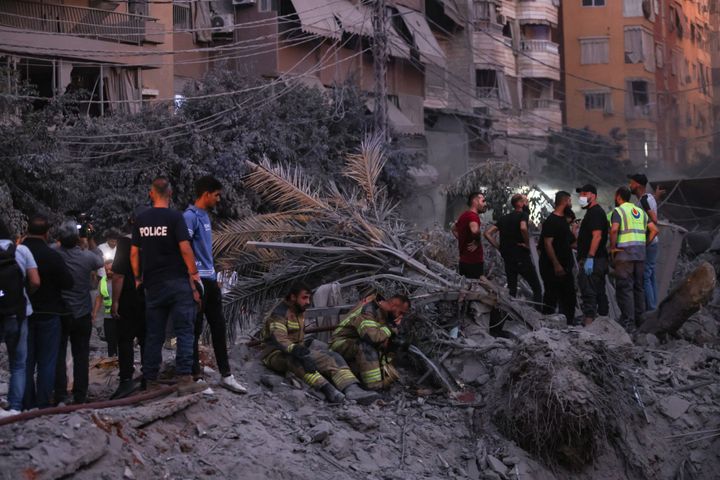 Rescuers rest near a crater at the scene of Israeli air strikes in the Haret Hreik neighbourhood of Beirut's southern suburbs on September 27, 2024. (Photo by IBRAHIM AMRO/AFP via Getty Images)