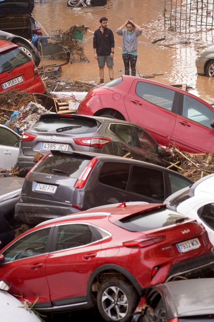 Residents look at cars piled up after being swept away by floods in Valencia, Spain.