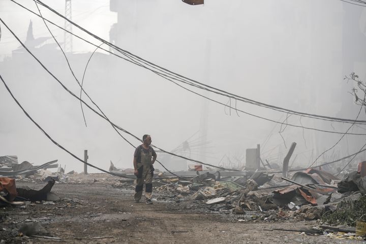 A man walks as smoke rises from destroyed buildings at the site of an Israeli airstrike in Choueifat, southeast of Beirut, Lebanon, Monday, Oct. 7, 2024. (AP Photo/Bilal Hussein)