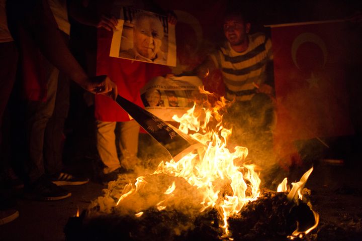 Government supporters burn pictures depicting Islamic cleric Fethullah Gulen during a protest in Taksim Square, in Istanbul, on July 18, 2016.