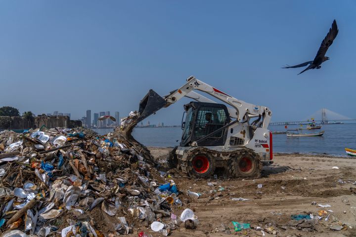 An excavator cleans up plastic and other waste materials on Mahim Beach on the Arabian Sea coast in Mumbai, India, on April 22, 2024.