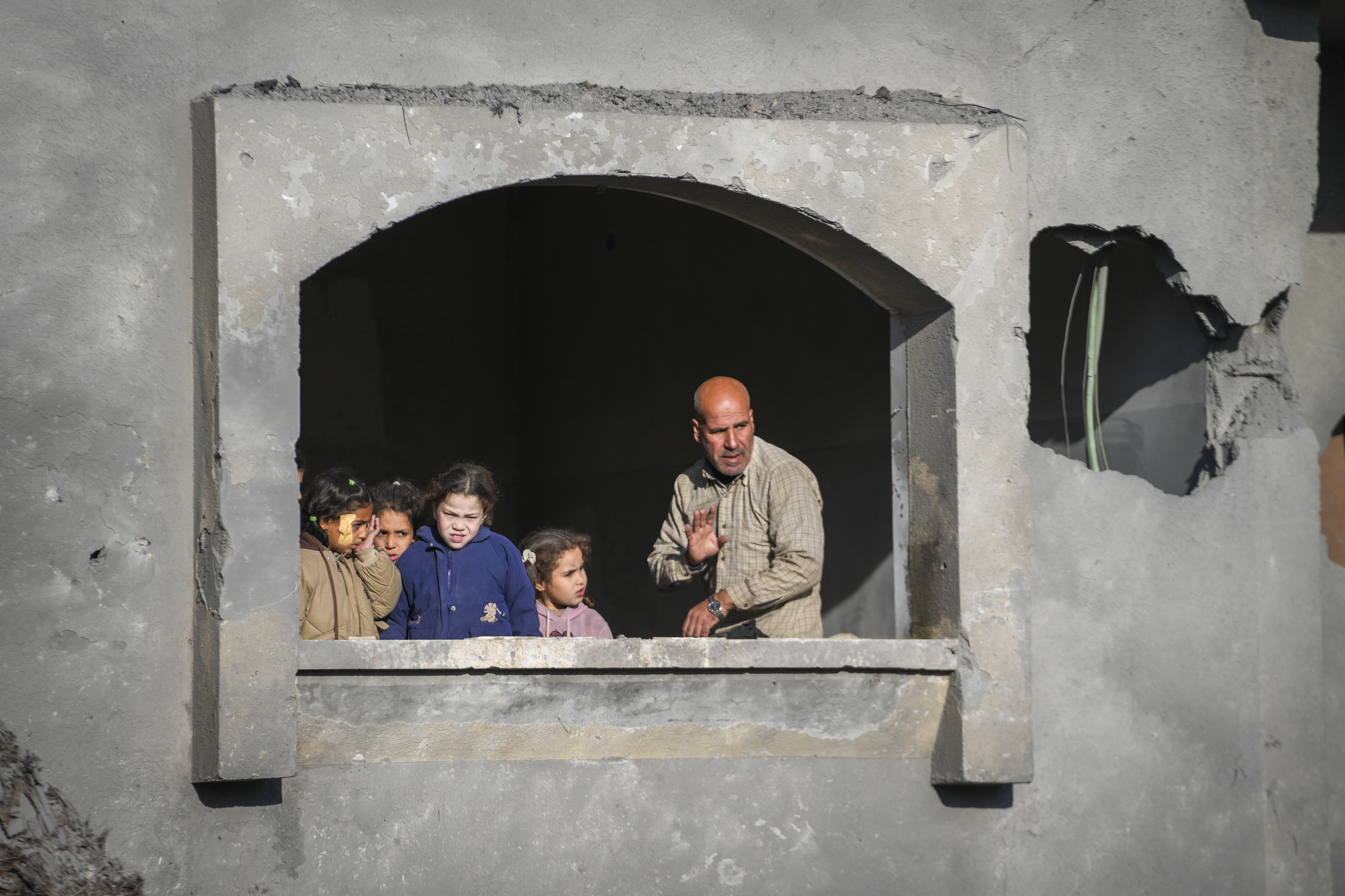 Neighbors watch the funeral procession of the victims of an Israeli strike on a home late Saturday, in Deir al-Balah, central Gaza Strip, Sunday, Dec. 22, 2024. At least eight people were killed according to the hospital which received the bodies. (AP Photo/Abdel Kareem Hana)