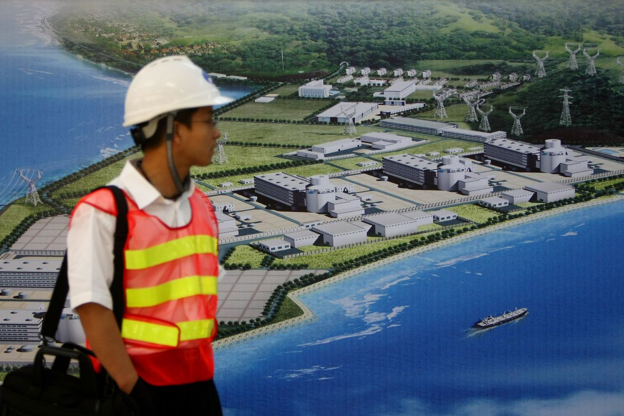 A journalist passes by a rendering of the Sanmen Nuclear Power Plant on June 4, 2009 in Sanmen of Zhejiang Province, China. 