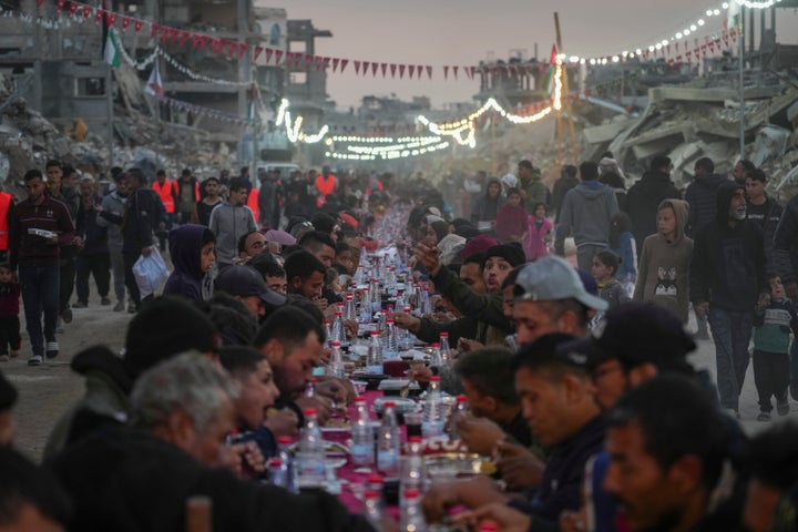 Palestinians sit at a large table surrounded by the rubble of destroyed homes and buildings as they gather for iftar, the fast-breaking meal, on the first day of Ramadan in Rafah, southern Gaza Strip, Saturday, March 1, 2025 (AP Photo/Abdel Kareem Hana)