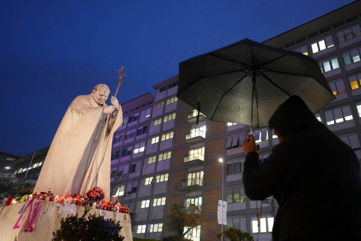 A man shelters from the rain as he prays for Pope Francis in front of the Agostino Gemelli Polyclinic, where the Pontiff has been hospitalized since Feb.14, in Rome, Saturday, March 1, 2025. (AP Photo/Kirsty Wigglesworth)