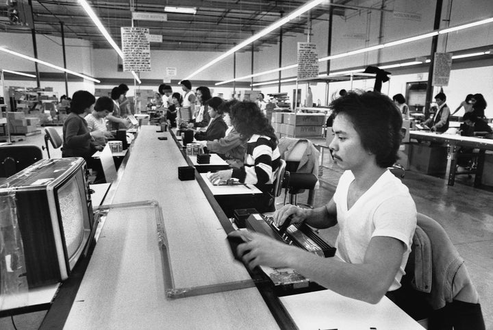 Workers assemble computer chips along a conveyor belt in a Silicon Valley factory.