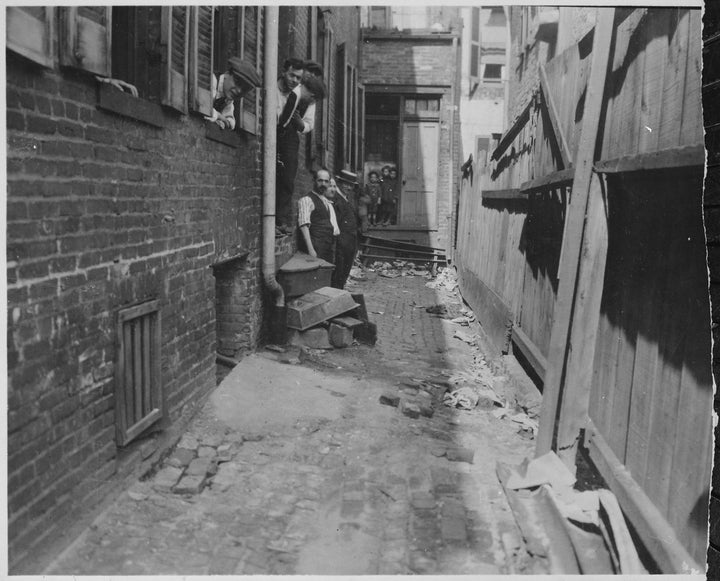 Photograph of workers and children in the alley outside of a garment factory, Baltimore, Maryland, 1921. Image courtesy US National Archives.