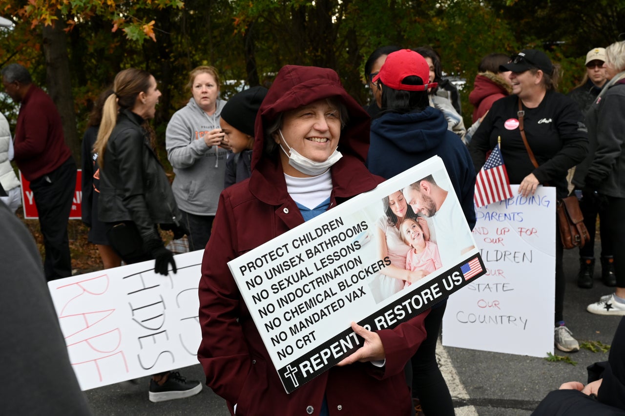 A woman holds a sign listing conservative talking points ahead of a school board meeting in Loudoun County, Virginia.