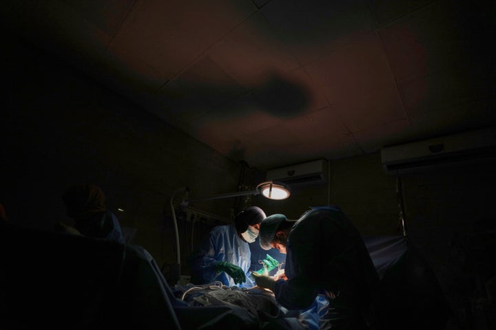 Dr. Abeer Al-Gharbawi (L) performs surgery using a battery-powered light during a power outage at Al-Shifa Hospital in Gaza City, on July 4, 2025.